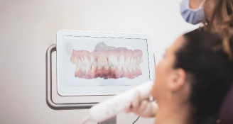 Patient viewing digital 3D scan of teeth on screen during dental examination