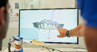 Dental professional pointing at 3D model of teeth on computer screen for digital treatment planning