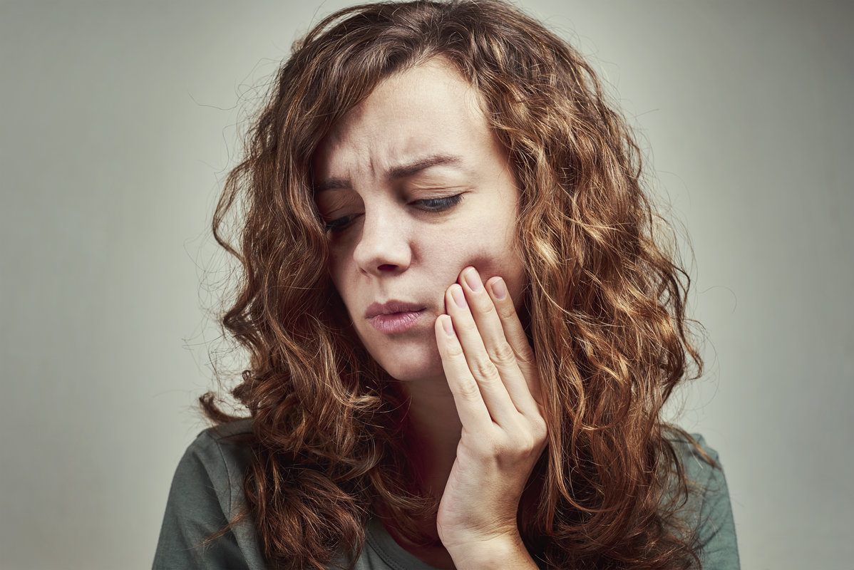 Woman suffering from toothache, touching cheek with hand, close up